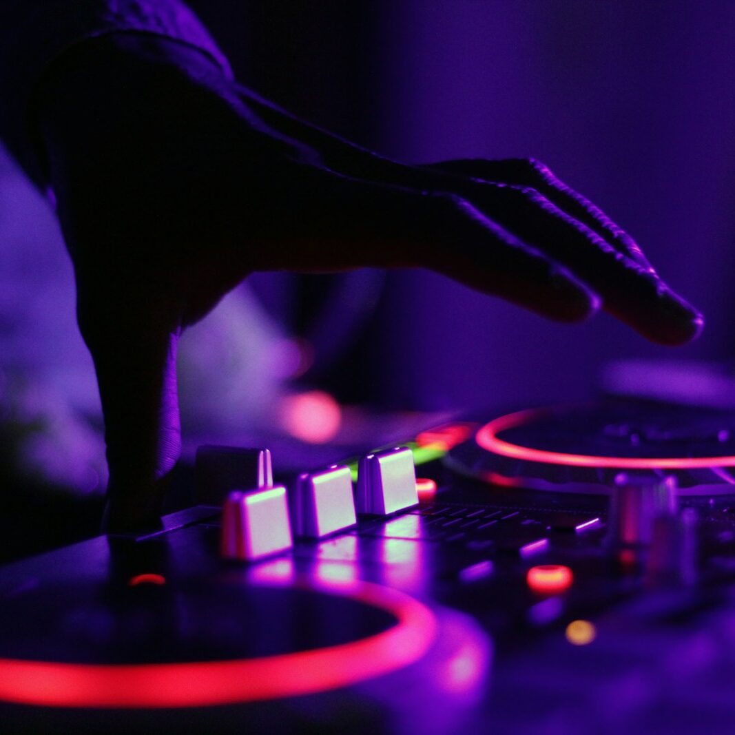 selective focus silhouette photography of man playing red-lighted DJ terminal